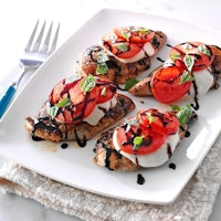 grilled chicken with tomatoes and basil on a white plate