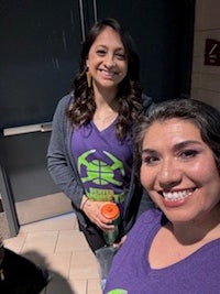 two women in purple t - shirts standing next to each other